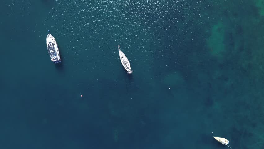 Aerial top down drone view of small boats floating in a tropical bay in Puerto Galera Philippines featuring crystal clear turquoise water, calm sea and vibrant colors ideal for travel and diving.