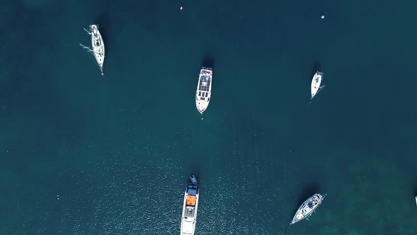 Aerial top down drone view of small boats floating in a tropical bay in Puerto Galera Philippines featuring crystal clear turquoise water, calm sea and vibrant colors ideal for travel and diving.