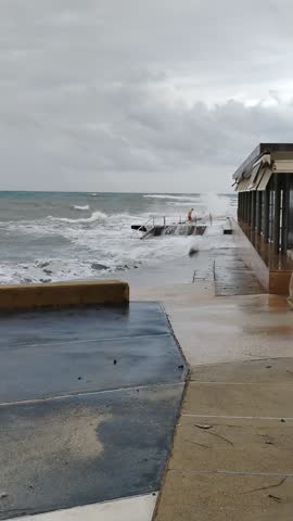 Man getting out of stormy sea as large waves brake over him.