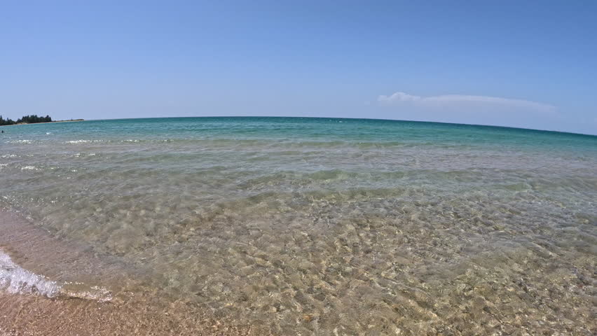 Big beautiful waves of crystal clear water crash onto the beach of Lake Michigan. Water is turquoise colored with views to the sand below. Unspoiled nature located within Wilderness State Park in Northern Michigan, USA. Wide angle view.