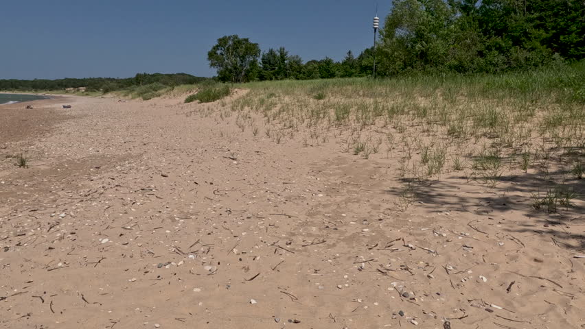Beach and Sand Dune Landscape on Lake Michigan. Moving through sand dunes with wild marram grass on the beach of Lake Michigan. Coastal vegetation ecosystem located within Wilderness State Park in Northern Michigan, USA.