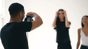 Professional photographer capturing female models during stylized portrait session within minimalist white studio environment, showcasing contemporary fashion photography workflow - Powered by Shutterstock - Get 15% off with code: PIKWIZARD15