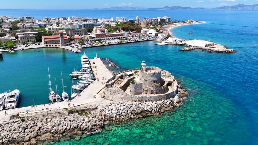 Aerial drone cinematic video of famous Saint Nicholas Fortress built in entrance of Mandraki harbor next to where Colossus of Rhodes was initially built, main town of Rhodes island, Dodecanese, Greece