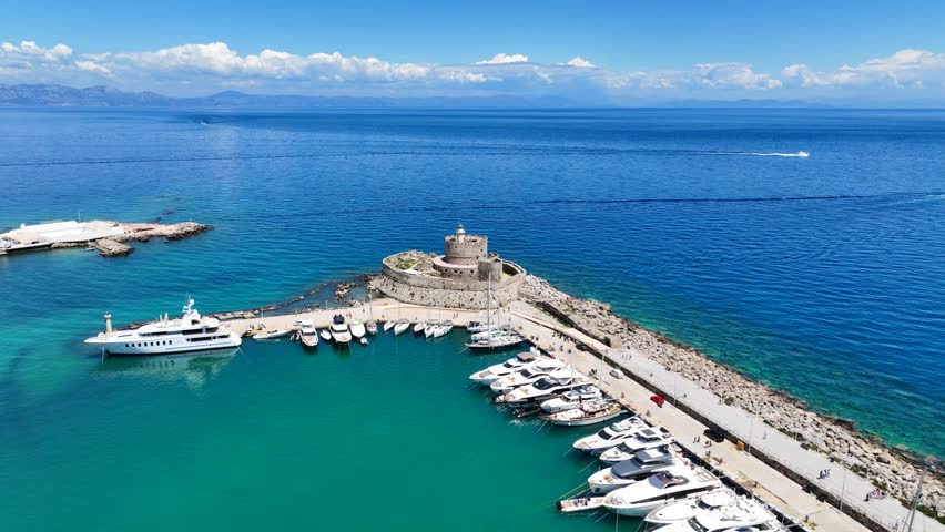 Aerial drone cinematic video of famous Saint Nicholas Fortress built in entrance of Mandraki harbor next to where Colossus of Rhodes was initially built, main town of Rhodes island, Dodecanese, Greece