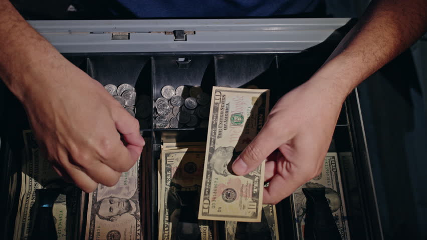 Cashier hands placing US dollar banknotes into cash register while giving change to customer, close up view of retail payment process with American currency and coin tray. High quality 4k footage