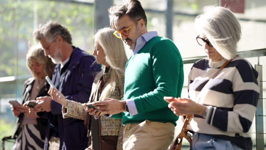 Diverse group of mature and senior people absorbed in their smartphones. Technology addiction and digital dependency concept in modern society