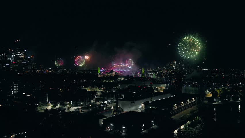 Cinematic 4K drone footage of Sydney New Year’s Eve fireworks exploding above Sydney Harbour at night, illuminating the water and skyline with vibrant colours during a spectacular city celebration.