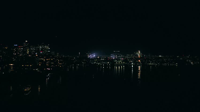 Cinematic 4K drone footage of Sydney New Year’s Eve fireworks exploding above Sydney Harbour at night, illuminating the water and skyline with vibrant colours during a spectacular city celebration.