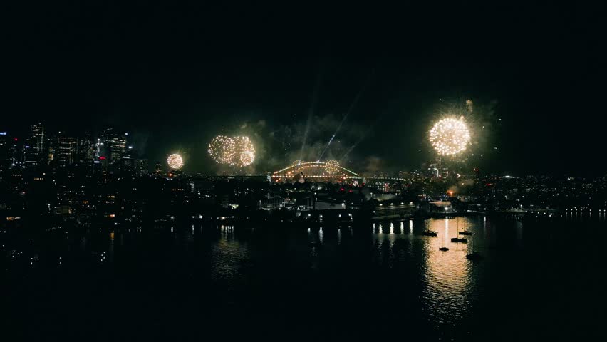 Cinematic 4K drone footage of Sydney New Year’s Eve fireworks exploding above Sydney Harbour at night, illuminating the water and skyline with vibrant colours during a spectacular city celebration.