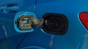 Man plugging in a luxury blue hybrid car at a home charging station, recharging his electric vehicle, highlighting eco-friendly transportation and sustainable living. - Powered by Shutterstock - Get 15% off with code: PIKWIZARD15