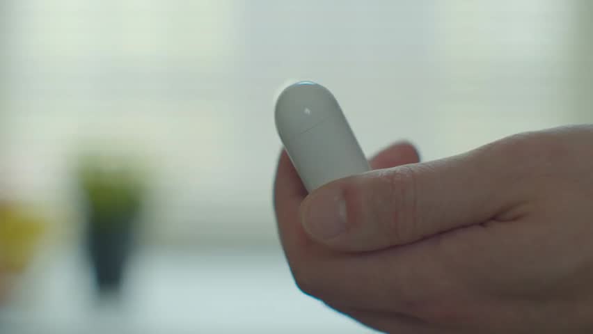 Close-up of a young man taking wireless earphones from their case, highlighting modern technology, audio devices, and everyday tech use.