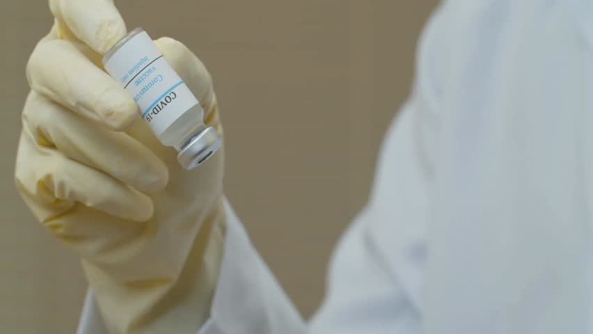 Doctor holding COVID-19 vaccine vial and syringe, coronavirus prevention, immunization, healthcare, medical research, and pandemic safety concept.