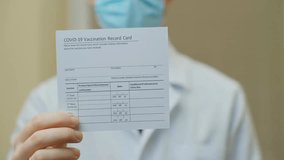 Male doctor holds COVID-19 vaccine vials and a vaccination card, representing health passport, immunity proof, and coronavirus recovery concept. - Powered by Shutterstock - Get 15% off with code: PIKWIZARD15