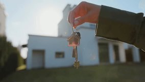 Key ring with house keychain in a hand on the background of a home, symbolizing real estate purchase, property ownership and buying a new house. - Powered by Shutterstock - Get 15% off with code: PIKWIZARD15