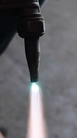 Close-up of a professional gas welding torch emitting a focused blue and yellow flame used for industrial metalwork.