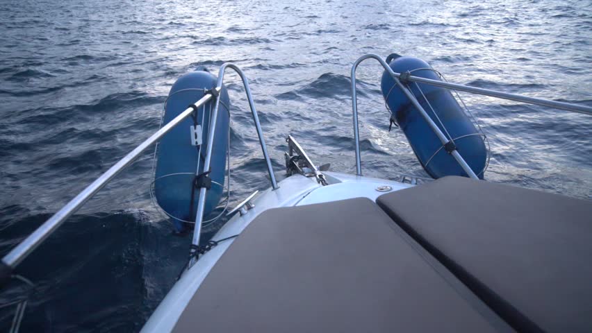 Boat ocean sailing yacht cruising through choppy blue waves during evening twilight travel