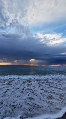 Dynamic coastal scene transitions from stormy clouds to a serene ocean view, capturing waves crashing on the shore with vibrant colors in the sky at dusk