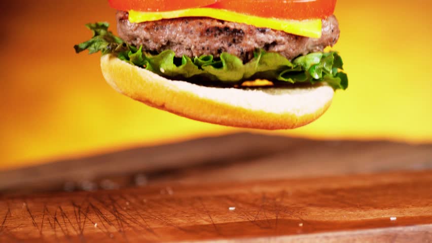 Fast food beauty shot featuring a juicy beef cheeseburger with layered meat, melted cheese, fresh onion, and ripe tomato. Rich textures and appetizing presentation make it ideal for food advertising, restaurant promos, menu visuals, and commercial content.