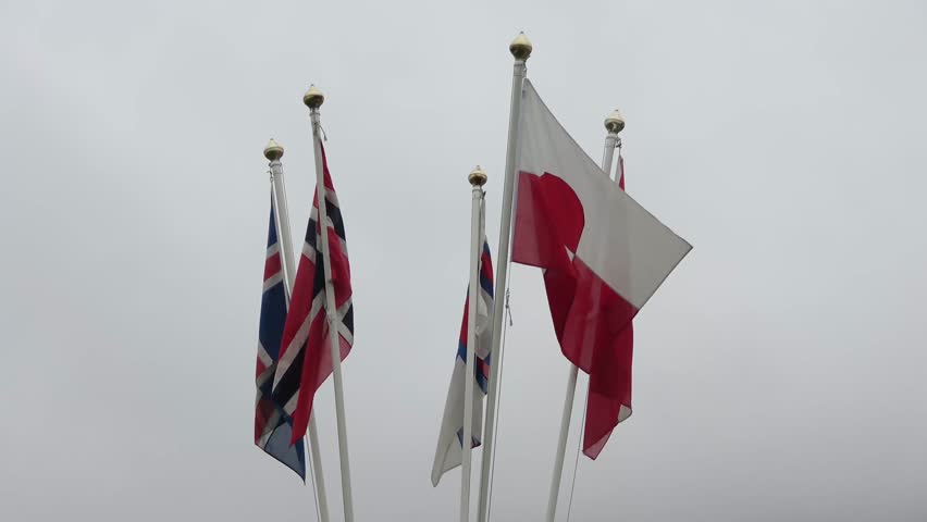 National flags of Iceland, Norway, Denmark, and Greenland blowing in the wind on flagpoles