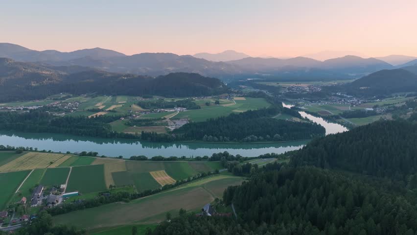 Cinematic drone footage of Drava river during blue hour, deep colors, calm water, soft gradients, evening stillness, smooth aerial movement, atmospheric summer scene