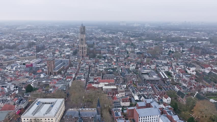 Aerial drone view of Utrecht city center with the iconic Dom Tower dominating the skyline on winter day, historic Dutch architecture, medieval streets, and urban rooftops in one of the oldest cities in the Netherlands