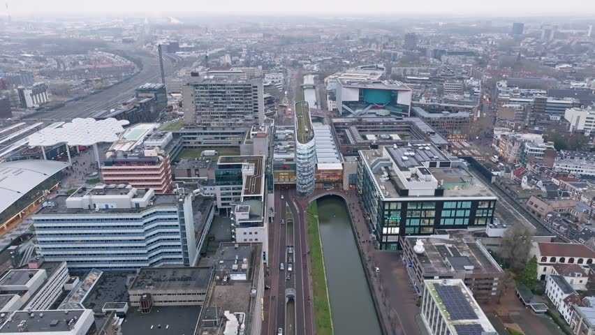 Aerial drone approaching Hoog Catharijne, the modern shopping and transit complex in Utrecht city center, showing contemporary architecture, retail spaces, and its connection to Utrecht Central Station