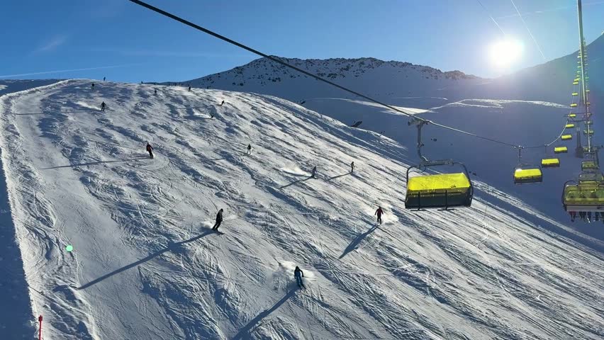 A sunny day of skiing at the Parsenn ski resort in Davos Klosters, Switzerland. There are skiiers and snoboarders on the piste.