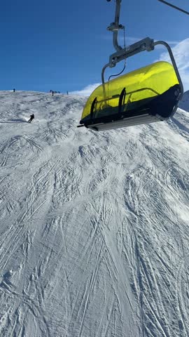 A sunny day of skiing at the Parsenn ski resort in Davos Klosters, Switzerland. There are skiiers and snoboarders on the piste.