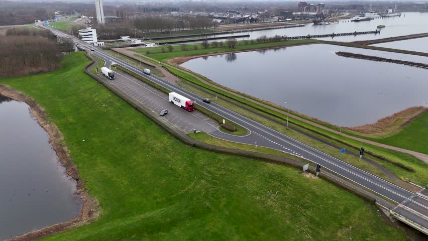 Scenic Route Beside Water With Traffic, Serene Coastal Pathway With Vehicles And Reflective Ponds