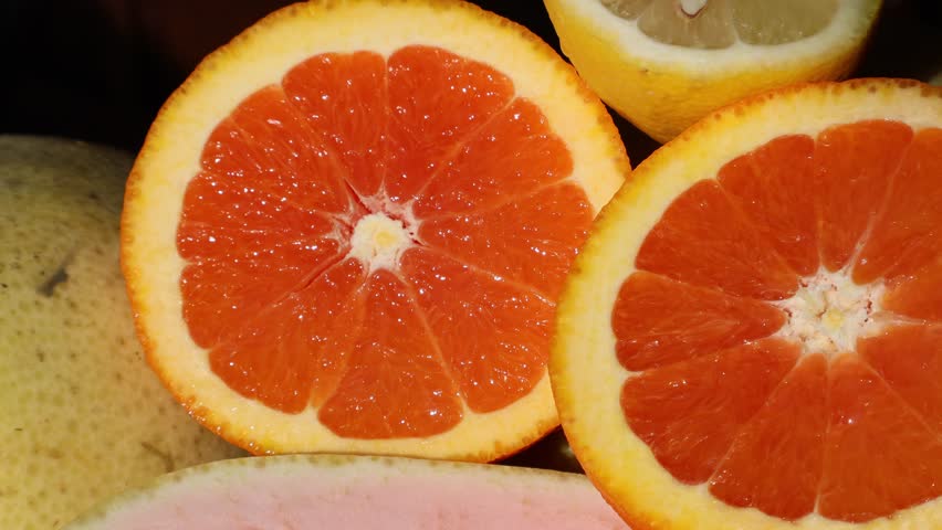 Close-up of a citrus fruit, cara cara orange, a type of navel orange, in halves with other tropical fruits like pomelos, lemons, and Thai kaffir lime displayed on the sides. November 23, 2025, Florida. For more photos and videos, check my portfolio!