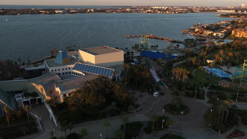 Galveston Island, Texas, United States – November 2024:
Aerial footage featuring a wide establishing shot as the drone gently pulls back, revealing multiple pyramids at Moody Gardens, adjacent parking lots, and the surrounding bay under soft evening light.