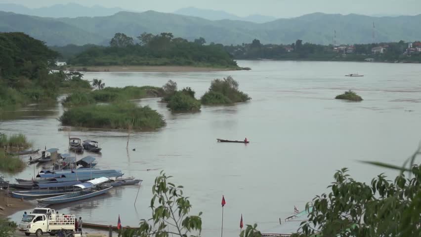 The atmosphere of people loading goods and driving cars and boats at a port in Huay Xai town, Laos.