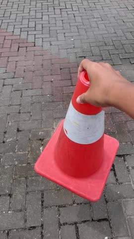 Slow motion Vertical shot of men hand holding traffic cone, lost his grip and drop it to the road