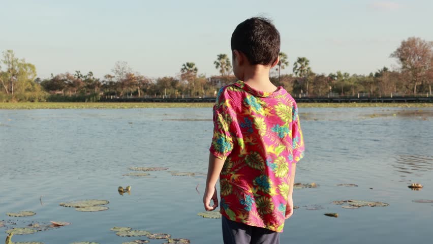 Child boy in a lake at sunset 