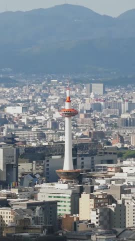 Vertical Aerial tilt up Japan Kyoto Tower, famous iconic landmark, urban town buildings