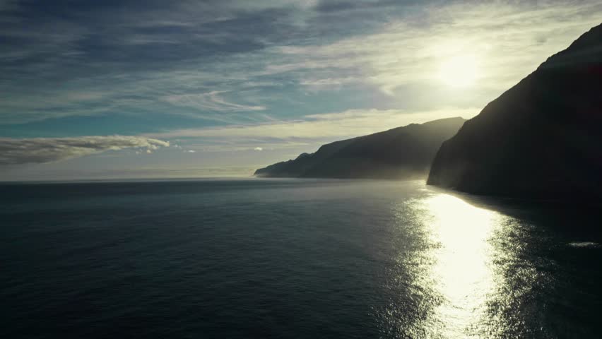The sun rises over the mountains on the seashore. View from the drone from the sea
