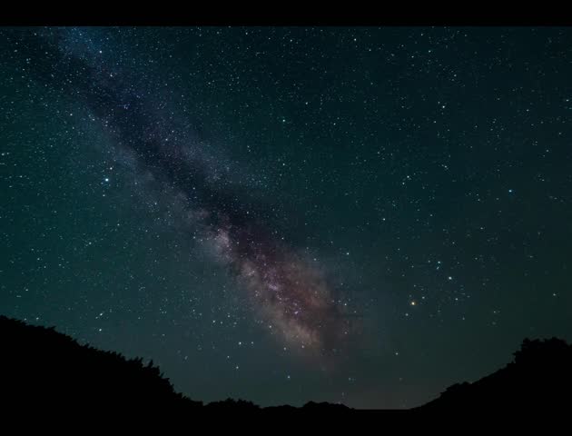 Stunning astrophotography captures the Milky Way galaxy stretching across a dark night sky above a mountain silhouette video