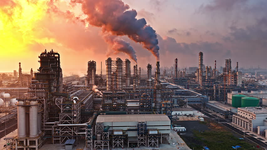 Aerial shot of an oil refinery and chemical plant industrial complex with smoke stacks emitting smoke, causing air pollution.