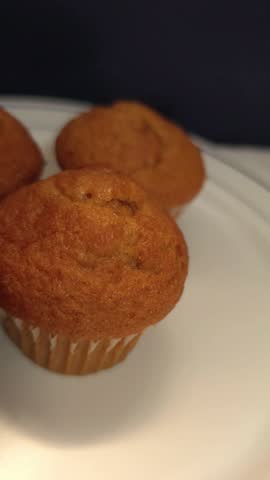 delicious golden brown muffins in white paper liners on a plate.