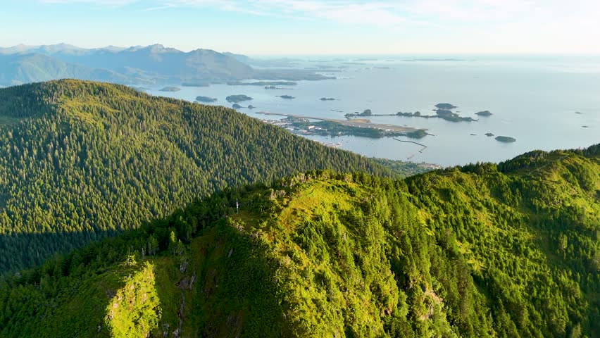 Aerial view of Sitka mountains and ocean, with green forests meeting the blue waters, creating a vibrant contrast in the Alaskan landscape, Sitka, Alaska, United States.