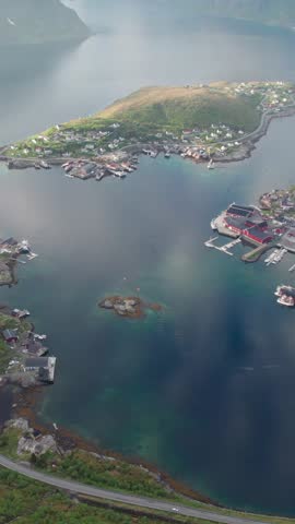 Stunning aerial backward shot from the top of Reinebringen mountain over Reine village, Norway