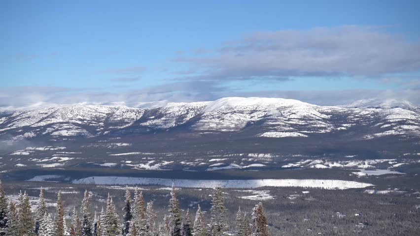 Spectacular panoramic view of snow-covered mountains, forests, and the frozen landscape of the Yukon wilderness near Whitehorse, Canada on a sunny day