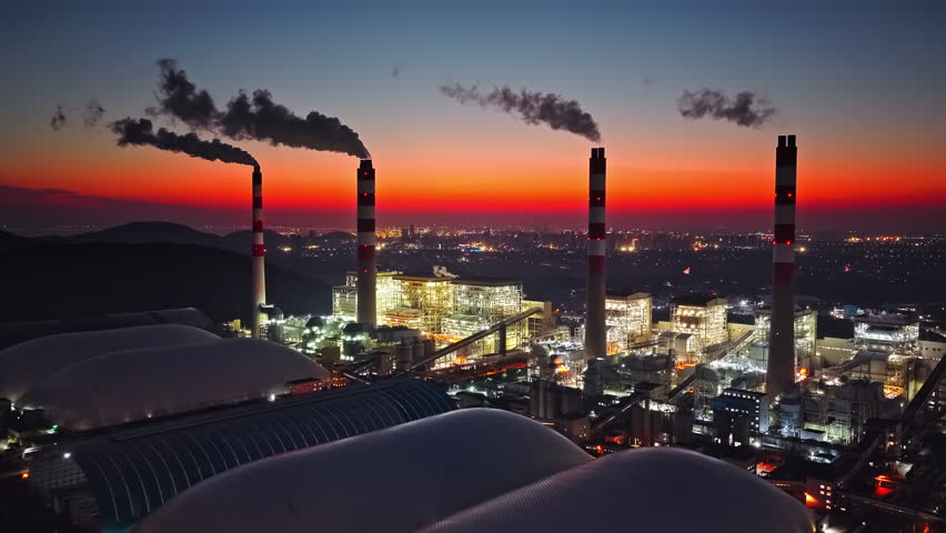 Aerial shot of thermal power plant and smoking chimneys at night