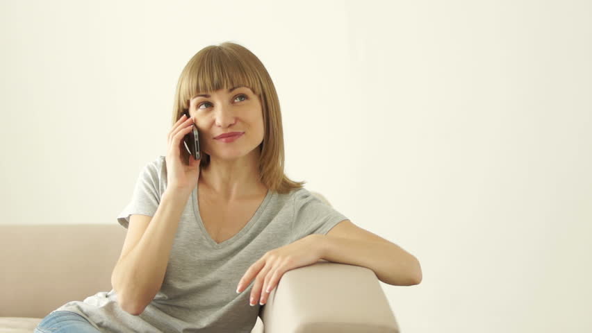 Cute girl sitting on couch and talking on the phone
