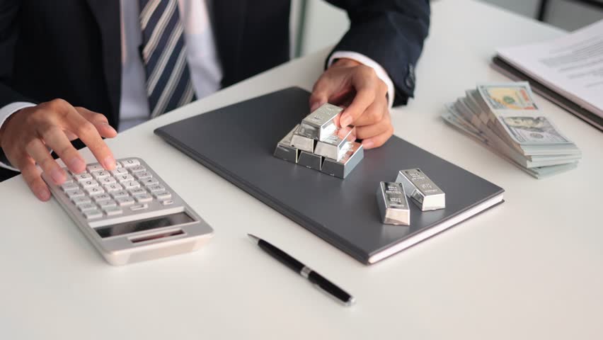 Silver bars on table. Businessman investing in precious metals to protect asset against inflation, currency depreciation.