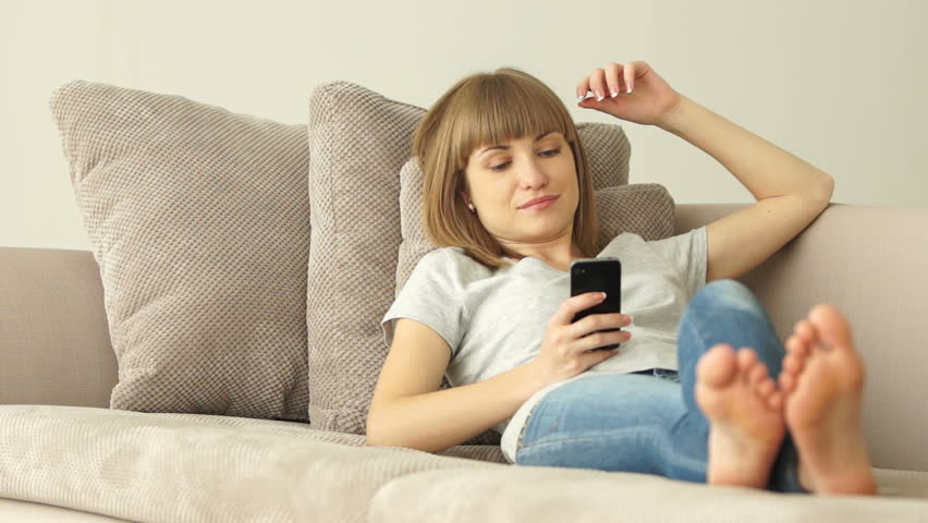Girl resting on the couch and holding a phone

