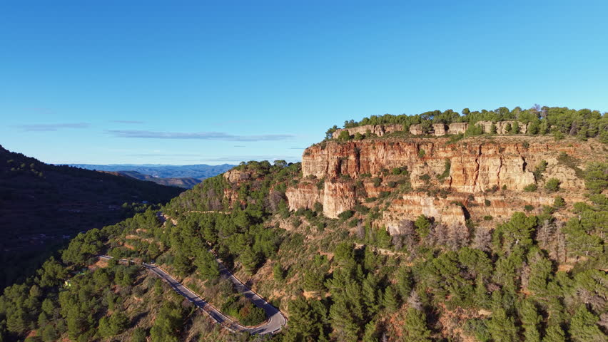 Push-in aerial shot over the Sierra Calderona Natural Park in the Valencia region of Spain, showing rocky mountain terrain glowing in warm golden evening light with scenic depth