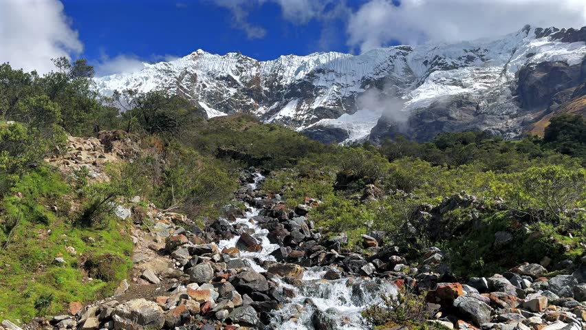 Peruvian Andes Humantay Laguna Lake Trek trail rocky creek river Peru Perú Salkantay glacier high altitude prominent peaks morning blue sky clouds sunny Anta province dry rainy season static shot
