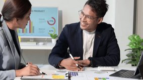 Two asian colleagues collaborating and analyzing charts and graphs together during a business meeting - Powered by Shutterstock - Get 15% off with code: PIKWIZARD15