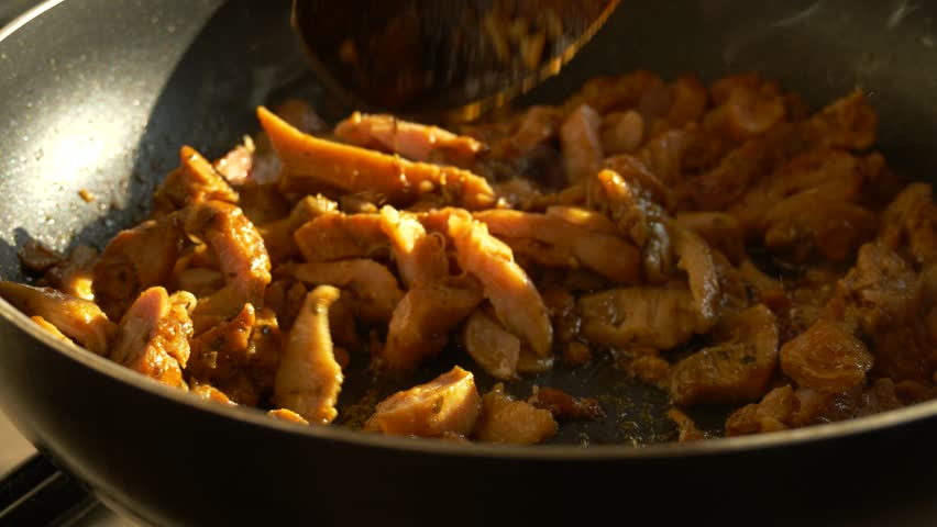 Close-Up of Cooking Meat Stirred in Pan with Wooden Spoon